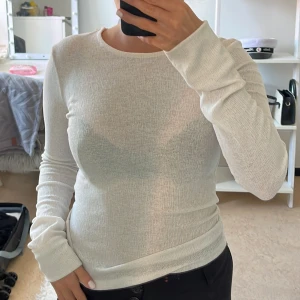 Vit ribbad långärmad tröja - Säljer en vit, ribbad långärmad tröja med rund hals. Tröjan är figurnära, stretchig känsla som gör den superbekväm. Den är genomskinlig men sitter nog lite bättre på någon annan än mig, skulle säga att det är mer en S än xs