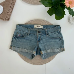 Lågmidjade Jeansshorts  Hollister  - Ett par ljusblå lågmidjade jeansshorts från Hollister i storlek W25 (XS). Rakt över midjemått: 37cm. Längd: 20cm. Gren: 16cm. D25