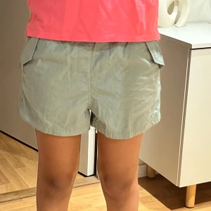 Ljusgröna cargoshorts med fickor - Snygga ljusgröna cargoshorts med praktiska fickor på sidorna och avslappnad passform. Perfekta för varma dagar och har en enkel, stilren look. Tillverkade i ett lätt bomullsmaterial som känns skönt mot huden.