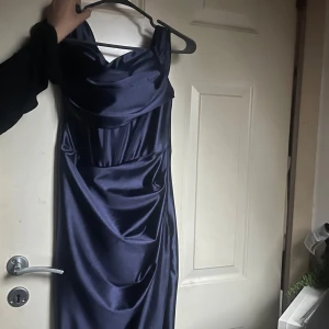 Mörkblå långklänning i satin - Säljer en elegant mörkblå långklänning med draperad halsringning och smala axelband. Klänningen har en glansig satinlook som ger en lyxig känsla och sitter figurnära. Perfekt för dig som vill sticka ut.       Priset kan diskuteras, fler bilder kan skickas 🤍