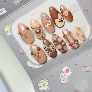 Bruna press-on naglar med björnmotiv - Söta press-on naglar i olika nyanser av brunt och beige med gulliga björnmotiv, hjärtan och rutiga detaljer. Naglarna är mandelformade och har 3D-detaljer som öron på vissa naglar. Perfekt för dig som vill ha en unik och lekfull nageldesign.