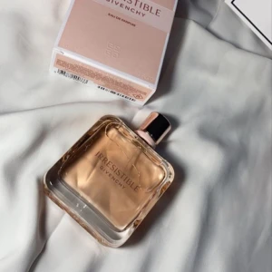 Givenchy Irresistible Eau de Parfum - Givenchy Irresistible Eau de Parfum med en elegant fyrkantig glasflaska och ljusrosa doftvätska. Flaskan har en stilren roséguldfärgad kork och subtila geometriska mönster. Perfekt för dig som gillar lyxiga och feminina parfymer. Endast provtestat.