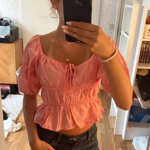 Rosa puffärmad blus med volang - Intressekoll!!!!! ❤️osäker om jag vill sälja men lägger ut o ser ifall någon vill köpa!! Supersöt rosa blus med puffärmar och volang nertill. Smockad midja och knyt fram ger en feminin vibe. Kan bäras både på axlarna och offshoulder. Perfekt för vår och sommar, och riktigt skön i lätt bomull.