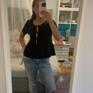 Svart blus med knyt framtill från Gina Tricot - Supersöt svart blus från Gina Tricot med tre knyt framtill som ger en unik look. Modellen har korta ärmar och lätt utställd passform nedtill. Ser skrynklig ut på andra bilden men kommer strykas så att den är i sitt finaste skick vid köp!💗💗 Väldigt bra skick