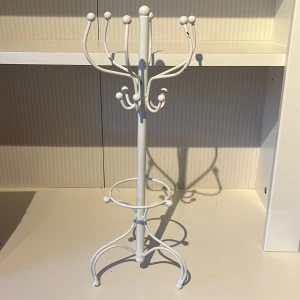 Vit smyckeshållare i metall - Snygg smyckeshållare i vitlackerad metall med flera krokar för att hänga ringar, armband, toffs och halsband. Stativet har en stilren och modern design med rundade detaljer och stabil fot. Perfekt för att organisera dina favoritsmycken på ett trendigt sätt. Inga skador. 