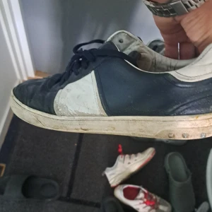 Flycrews - Snygga sneakers i svart och vitt med klassisk design. Skorna har svarta snören, rund tå och platt sula. Tillverkade i skinn med kontrasterande paneler och en vit sula som ger en sportig vibe. Perfekta för dig som gillar en stilren och tidlös look.