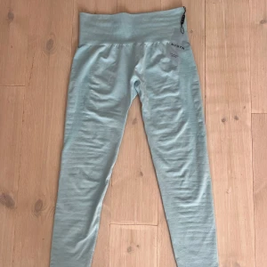 Ljusblå leggings från NVGTN - Supersnygga ljusblå leggings från NVGTN med hög midja och tight passform. De är sömlösa och har en bred ribbad linning som sitter skönt och ger extra stöd. Har en liten skugga baktill som er en snygg contour för rumpan. Ny skick.