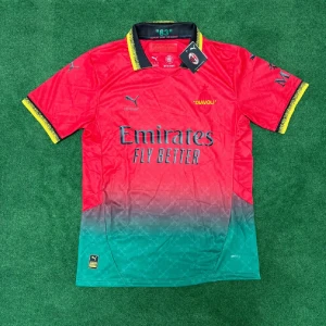 AC Milan Puma fotbollströja röd/grön - Snygg AC Milan fotbollströja från Puma med röd överdel och grön nedre del i snygg fade. Tröjan har gula detaljer på krage och ärmslut, samt tryck med 'Emirates Fly Better' och 'Diavoli'. Klassisk kortärmad modell i lätt funktionsmaterial.