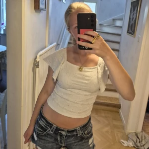 Vit blus med volangärm - Superfin vit blus med broderade detaljer och korta volangärmar från Kappahl. Toppen har fyrkantig ringning och är croppad. Inga defekter men väl använd! Stl 158/164