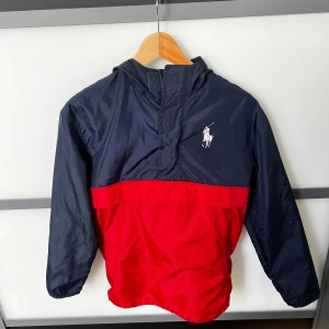 Ralph Lauren Anorak jacka - Anorak från Ralph Lauren i blått och rött. Med seglar flaggor på ryggen.