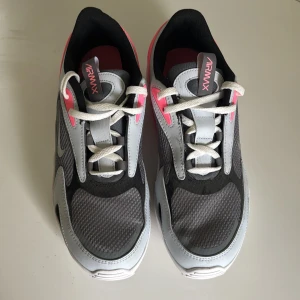 Nike Air Max sneakers grå/rosa - Nike Air Max sneakers i grått, svart och vitt med snygga rosa detaljer. Ovandel i mesh och syntet, vit sula med synlig Air Max-enhet och klassisk snörning. Skorna har en sportig vibe och passar perfekt för dig som gillar streetstyle.