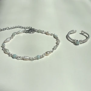 Amazonite Set - Setet innehåller: ✓ Ett handgjort armband ✓ En justerbar ring  Armband: Längd: 16,5 cm + 6,5 cm förlängningskedja Material: Rostfritt stål, äkta sötvattenspärlor och Amazonite (ädelsten)  Ring: Justerbar storlek Material: Rostfritt stål med äkta Amazonite (ädelsten)