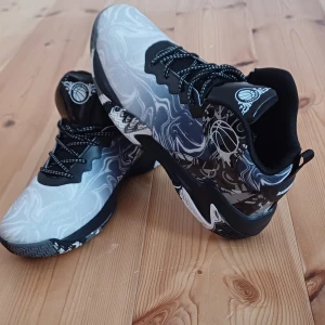 Svarta och vita basket sneakers - Oanvända snygga sneakers med svart och vit swirl-design och coola basketdetaljer på plösen. Skorna har snörning och en robust platt sula med mönstrad kant. Perfekta för dig som gillar sportig stil och unika mönster 