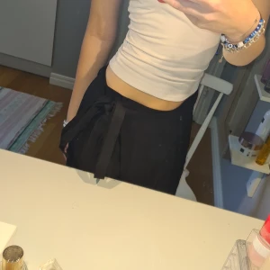 Svart omlottkjol med knytband - Svart lång omlottkjol med breda knytband i midjan. Kjolen har en stilren och enkel design som ger en snygg siluett. Perfekt att styla med crop top eller stickad tröja. Materialet känns lätt och flowy. Aldrig använd💕