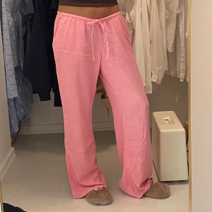 Rosa linnebyxor med snörning - Säljer ett par chill rosa linnebyxor med skön loose passform och snörning i midjan. Byxorna har raka ben och sidofickor, perfekta för varma dagar eller softa hemmakvällar. Lätta och luftiga i materialet, passar dig som gillar avslappnad stil.