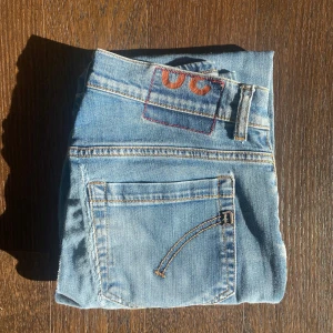 Dondup George - Säljer ett par skinny fit jeans från dondup i ljusblå denim med klassiska fem fickor och snygga kontrastsömmar. Jeansen har låg midja och smal passform hela vägen ner, perfekt för dig som gillar en modern och slimmad look.