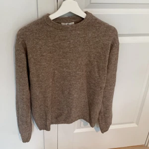 Beige stickad tröja från H&M - Mysig beige stickad tröja från H&M med rund hals och långa ärmar. Perfekt för dig som gillar enkel och clean stil. Materialet är mjukt och skönt, och passformen är normal. Snygg att matcha med jeans eller kjol för en chill look.