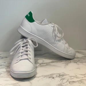 Vita Adidas sneakers med gröna detaljer - Vita Adidas sneakers med gröna detaljer pả hälen och tungan. Perfekta för en avslappnad och stilren look. Bara använda vid enstaka tillfällen.