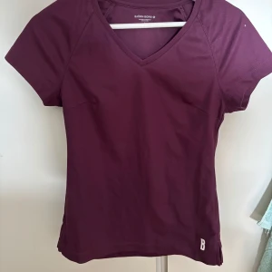 Träningströja från Björn Borg - Snygg vinröd/lila träningstshirt från Björn Borg med v-ringning och korta ärmar. Perfekt för träning. 💕