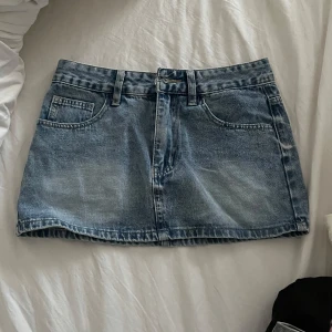 Blå jeanskjol med fickor - Snygg blå jeanskjol i klassisk modell med fickor fram och hällor för bälte. Kjolen är kort och har en lätt tvättad look som ger en cool vibe. Perfekt att matcha med en t-shirt eller hoodie för en avslappnad stil. Midjemått är 35cm längden är 32cm🩷