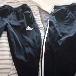 Svarta Adidas och Vans mjukisbyxor - Säljer ett gäng svarta mjukisbyxor från Adidas och Vans, samt ett par meshbyxor från YØRK med tryck. Adidasbyxorna har vita detaljer och logga, Vans har 'Off The Wall'-mönster och YØRK har ett coolt stadstryck. Perfekta för chill eller träning.