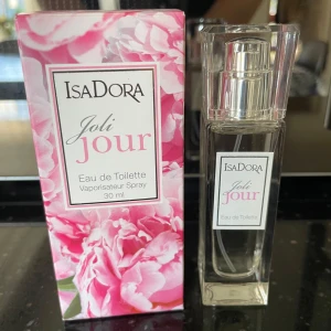 IsaDora Joli Jour Eau de Toilette 30ml - IsaDora Joli Jour Eau de Toilette i 30 ml flaska. Parfymen kommer i en elegant, genomskinlig glasflaska med silvrig spray och tillhörande ask med blommigt rosa mönster. Doften är feminin och fräsch, perfekt för dig som gillar blommiga toner.