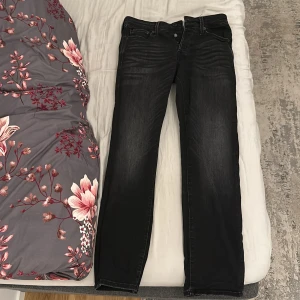 Svarta superstretch jeans Jack & Jones - Svarta jeans från Jack & Jones med superstretch för extra komfort. Modellen har klassisk femficksdesign, smal passform och snygga slitningar framtill. Perfekta för dig som vill ha både stil och rörelsefrihet. Materialet är jeans med stretch och midjan är normal.
