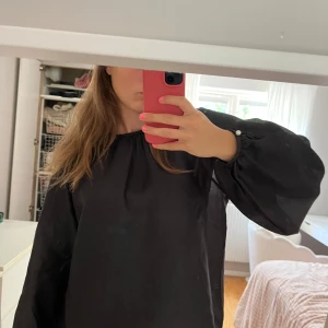 Långärmad svart blus  - Säljer denna mycket söta blus, köpt på MQ och märket är STOCKH LM. Den har vita knappar runt handlederna och även en i nacken. Använd max 3 gånger så inga tecken på detta! Säljer direkt för 180kr!