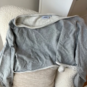 Grå offshoulder tröja från Junkyard - Säljer en grå  tröja från Junkyard. Tröjan har lång ärm och enkel design utan mönster eller detaljer, perfekt för chill dagar. Passformen är loose och materialet är tunt och skönt mot huden.