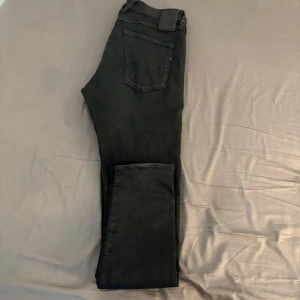 Replay Hyperflex svarta jeans, strl 34 - Svarta Replay Hyperflex Anbass jeans med klassisk femficksdesign och smal passform. Stretchigt material som ger grym komfort och rörelsefrihet. Snygga detaljer med Replay-logga på linningen och diskreta sömmar. Perfekt för dig som gillar stilrena och moderna jeans. Storlek 34/34.