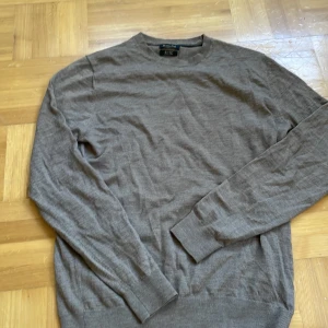 Brun merinoulltröja från Massimo Dutti - Snygg brun tröja från Massimo Dutti i mjuk merinoull. Klassisk rund hals och långa ärmar med ribbade muddar. Perfekt för dig som gillar stilrena och enkla plagg med skön passform. Passar dig som vill ha en basic tröja med lite lyxig känsla.