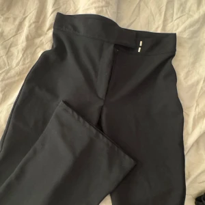 Svarta kostymbyxor från Nelly - Snygga svarta kostymbyxor från Nelly i storlek S. Byxorna har medel hög midja och utsvänga ben.  