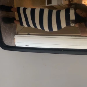 Randig långklänning i blått och vitt - Säljer en snygg långklänning med breda horisontella ränder i marinblått och vitt. Klänningen är ribbad och har en kroppsnära passform som framhäver siluetten. Perfekt för dig som gillar en stilren och modern look.