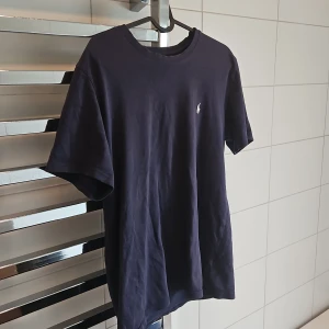 Mörkblå t-shirt från Polo Ralph Lauren - Kan gå ner i pris vid snabb affär. Snygg mörkblå t-shirt från Polo Ralph Lauren i mjuk bomull. Klassisk passform med korta ärmar och rund hals. Diskret vit logga broderad på bröstet ger en clean och stilren look. Perfekt för dig som gillar enkla och tidlösa plagg.