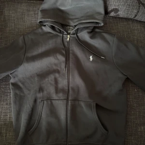 Ralph lauren zip hoodie  - Säljer en svart zip hoddie från Ralph Lauren som är i mycket bra skick. Den är inte använd särkilt mycket. Storlek M. Nypris 2300kr, mitt pris 900kr. Hör av er för fler bilder eller vid funderingar!