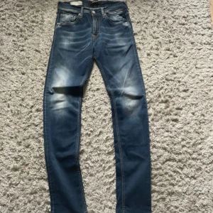 Replay jeans blå  - Snygga blå jeans från Replay med klassisk femficksdesign och raka ben. Jeansen har coola slitningar framtill och kontrastsömmar som ger en schysst look. Passformen är riktigt najs för dig som är runt 170 och materialet är mjukt jeans-tyg som sitter skönt hela dagen.