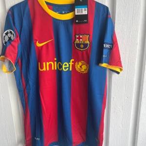 FC Barcelona Messi 10 matchtröja Nike - Säljer en FC Barcelona matchtröja med Messi 10 på ryggen. Tröjan är kortärmad och har breda blå och röda ränder, gula detaljer vid krage och ärmslut samt tryck från UNICEF och Champions League. Materialet är lätt och andas, perfekt för fotboll eller häng.