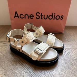 Beige sandaler Acne Studios - Snygga sandaler från Acne Studios i beige med croco-präglat mönster och grov svart sula. Remmarna har coola metallspännen och detaljer. Skriv vid frågor 💕