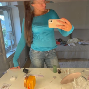 Turkos långärmad topp med båtringning - Snygg turkos långärmad topp med båtringning och slim passform. Tunn och mjuk, perfekt att styla med jeans eller kjol. Materialet känns som bomull eller syntet och sitter skönt mot kroppen. Enkel och fräsch design utan mönster eller detaljer.