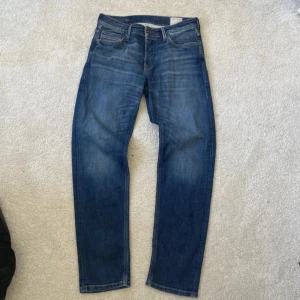 Blå tapered jeans från Jack&Jones - Snygga blå jeans med tapered fit och klassisk femficksdesign. Jeansen har en medelhög midja och raka ben som smalnar av nedtill. Tillverkade i slitstarkt denimtyg som ger en avslappnad och cool look. Perfekta för dig som gillar en modern men tidlös stil.