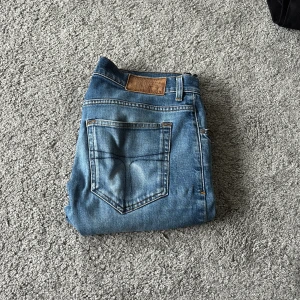 Blå tiger of Sweden 31/34 - Säljer ett par snygga blå jeans  tillverkade i Italien. De har klassisk femficksdesign, raka ben och en cool tvätt med lätt slitning. Passar dig som gillar en modern och stilren look med lite edge.
