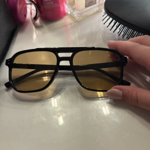 Svarta pilotglasögon med gula linser - Snygga pilotglasögon med svart ram och gula linser. Ramen är i plast och har en cool dubbelbrygga framtill. Perfekt accessoar för dig som vill sticka ut med en retro vibe.