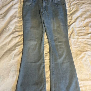Bootcut ljusblå jeans med stenar - Snygga ljusblå bootcut jeans från QI med coola silverfärgade stenar/ nitar vid fickorna både fram och bak. Jeansen har klassisk femficksdesign, knappstängning och bälteshällor. Perfekt för dig som gillar lite extra detaljer. En skärphälla är trasig men superenkelt att fixa! W30, L33