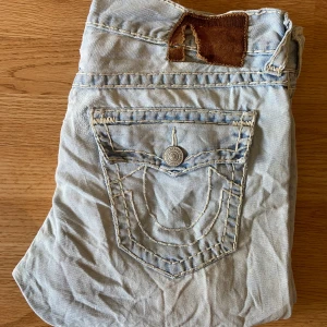 True Religion Jeans Geno Super T - Feta true religion jeans, straight, storlek 33, bra skick men ett litet knähål där det också saknas en knapp där bak, med riven backstab. 46cm midja, 112cm längd, 85cm innerben och 20cm ben öppning. 