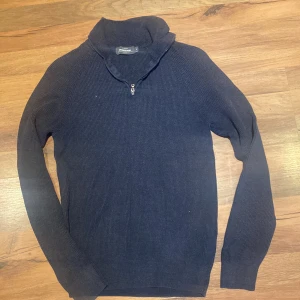 Mörkblå polotröja med half zip Dressmann - Snygg mörkblå polotröja från Dressmann Premium i storlek S. Tröjan är ribbstickad och har en praktisk half zip vid halsen. Materialet är en mjuk mix av bomull och lyocell som känns skönt mot huden. Perfekt för dig som gillar stilren och enkel design.