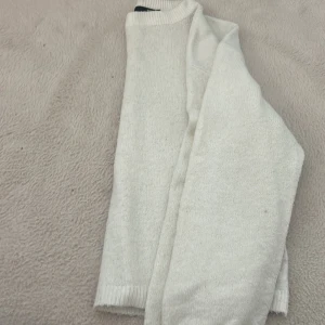 Vit stickad tröja - Snygg vit stickad tröja med ribbade muddar vid hals, ärmslut och nederkant. Tröjan har en enkel och clean design med långärmade ärmar och passar perfekt för dig som gillar minimalistisk stil. Perfekt att matcha med jeans eller kjol.