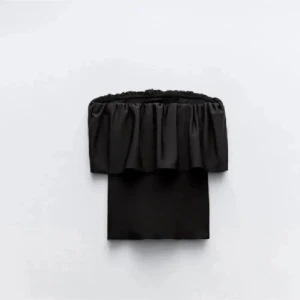 Svart bandeau tubtopp med volang - Säljer en svart bandeau tubtopp med bred volang upptill som ger en snygg och trendig look. Toppen är axelbandslös och har en tight passform som sitter på plats. Perfekt att matcha med jeans eller kjol för en cool stil.