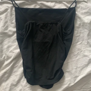 Svart ärmlös topp - Snygg svart topp med smala axelband och en enkel design. Perfekt för att matcha med olika outfits. Materialet är mjukt och bekvämt.