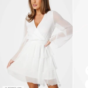 Vit omlottklänning med volanger - Elegant vit omlottklänning med v-ringning och långa ärmar. Använd en gång💞storlek xs