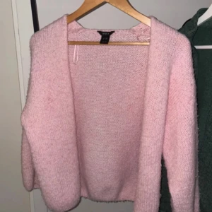 Rosa stickad kofta  - Mysig rosa stickad kofta från lindex! Perfekt för kyliga dagar med sin mjuka och bekväma passform. Koftan har långa ärmar och en öppen design utan knappar.